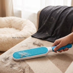 Lint brush removing pet fur from beige fabric couch upholstery, teal bristle pad.