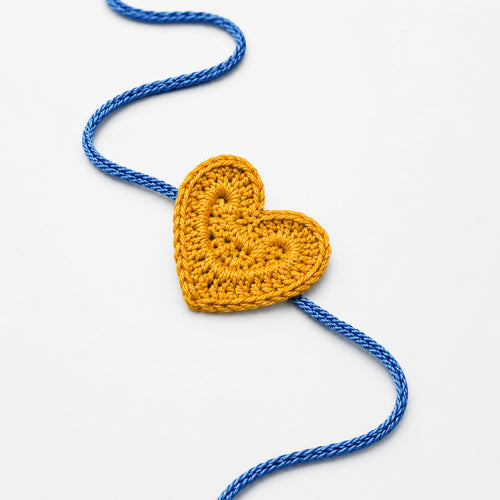 Heart-shaped crochet rakhi with yellow heart and blue braided thread