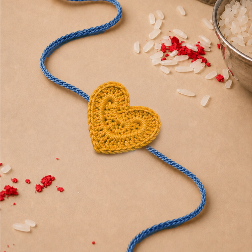 Heart crochet rakhi with yellow heart and blue thread, lying flat