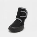 A single black ankle boot with gray trim and a hook-and-loop strap closure, shown from a three-quarters angle on a light gray background.